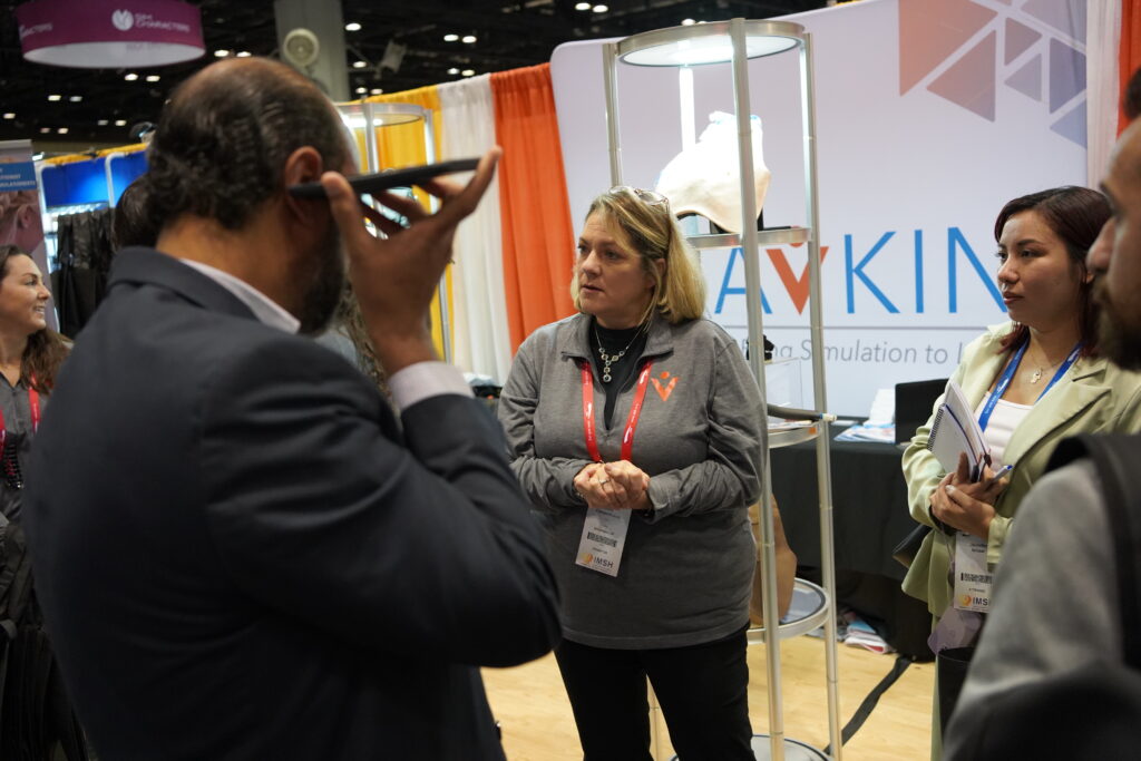 Amy Cowperthwait in front of Avkin Booth at IMSH 2023